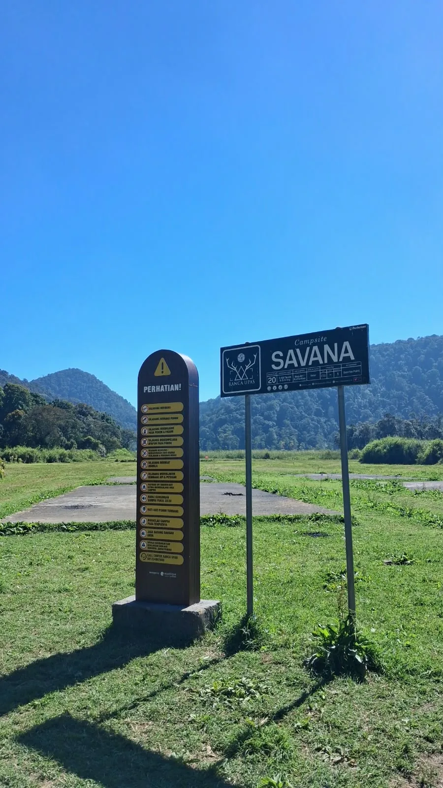 Papan Campsite Savana di lapangan terbuka berlatar perbukitan